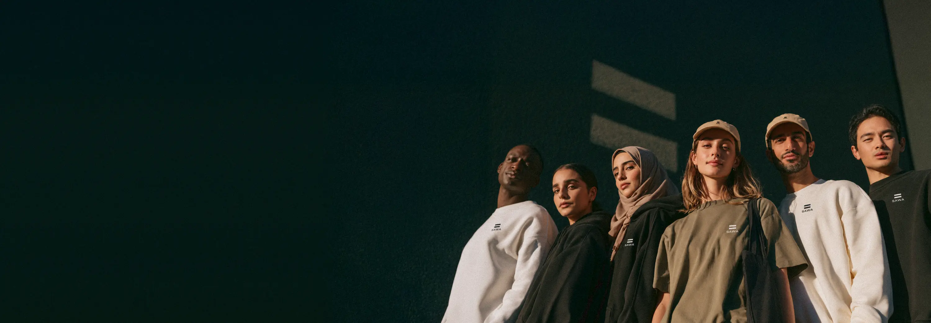 Six people wearing SAWA, seen from below in front of a dark wall where the light draws the equal sign
